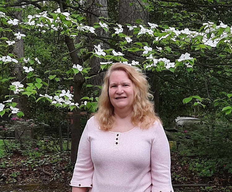Claudia Smarkola, healer and coach, standing in front of a dogwood tree