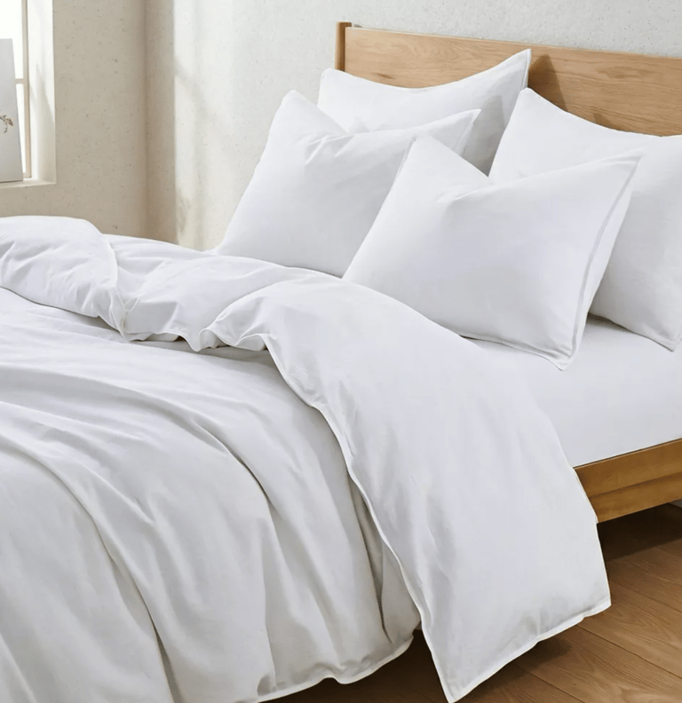 Crisp white cotton duvet cover and matching pillows on a modern wooden bed frame.