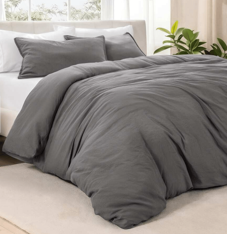 Modern charcoal grey duvet cover set on a white bed with matching pillow shams in a bright bedroom.