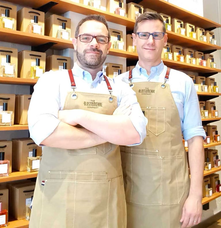 Kvepalų kūrėjai iš Valensijos, o už jų – lentyna pilna įvairių nišinių, jų kurtų kvepalų.