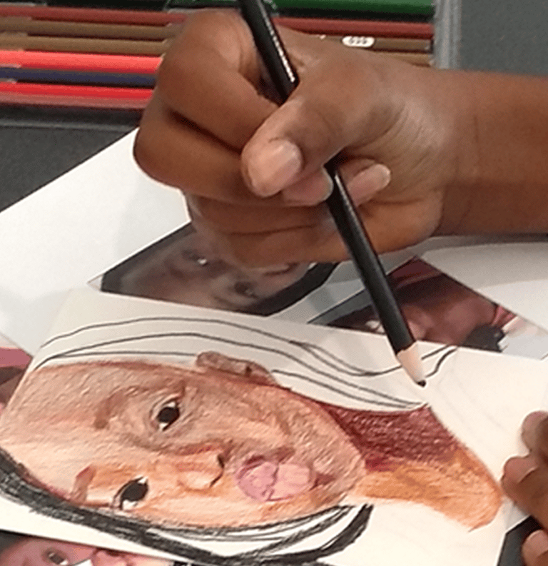 a teen holding a colored pencil and drawing a portrait of a person making a kissy face