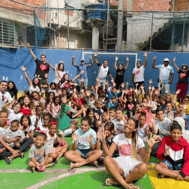 Voluntários e assistidos da ONG Eu Ajudo Como Dá, durante evento em quadra de comunidade