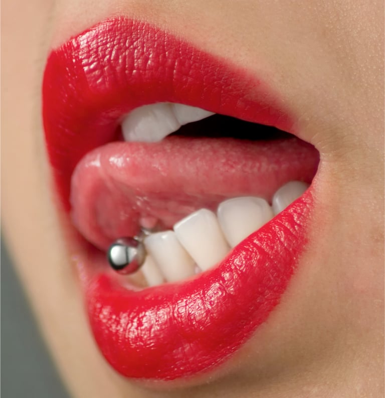 Close-up of red lips and white teeth with a silver barbell tongue piercing.