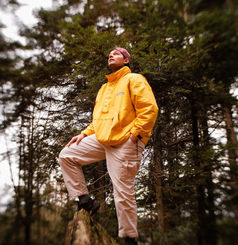 Homme sur un rocher qui regarde vers le ciel dans une forêt