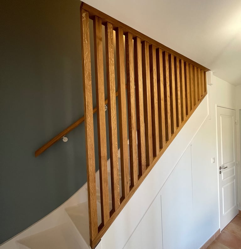 a staircase with a wooden handrail and a door