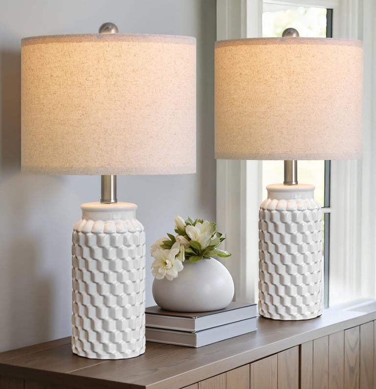 Pair of white textured ceramic table lamps with linen shades on a wooden dresser.