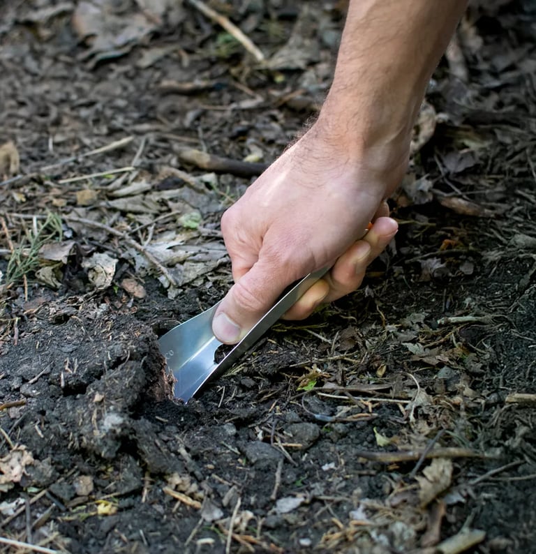 hand pushing backwards on bogerlco trowel to dig up soil