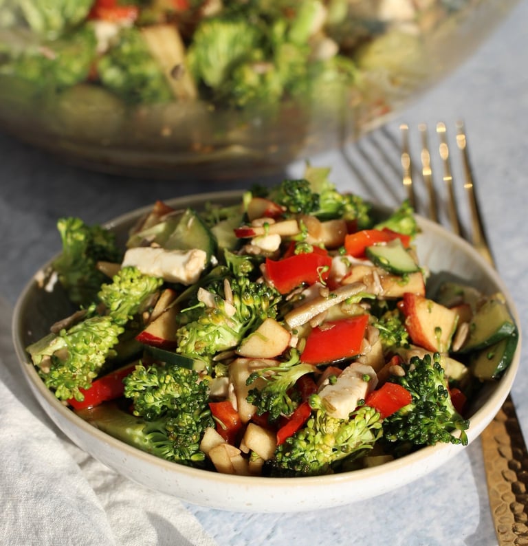 a bowl of broccoli salad with apple and broccoli