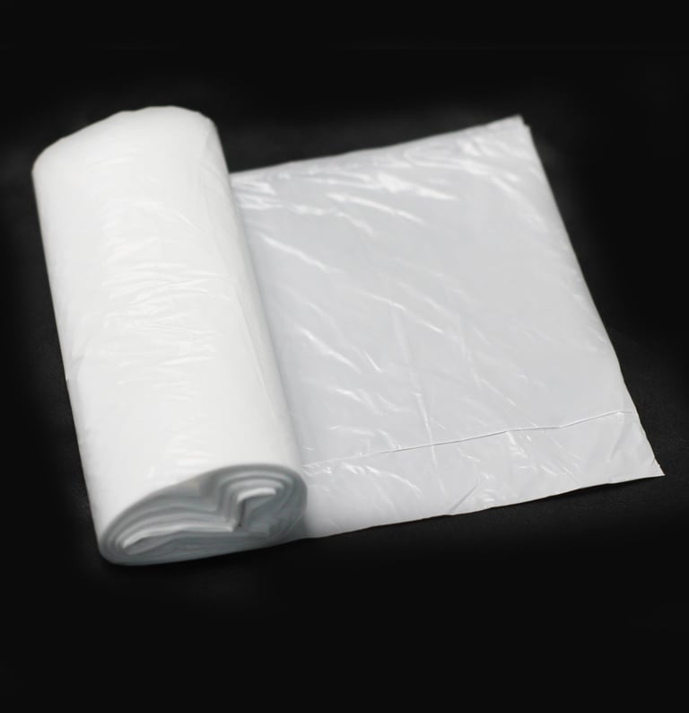 Rolo de saco para lixo branco no fundo preto.