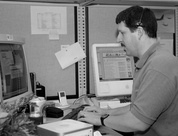 hombre respondiendo mensajes en computadoras viejas