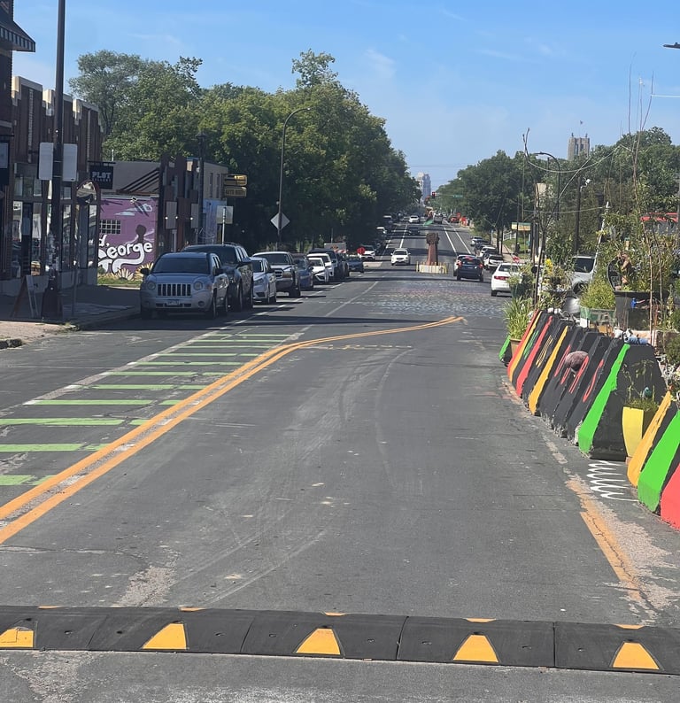 George Floyd Square parked cars, a black speed bump, and colorful traffic barriers.
