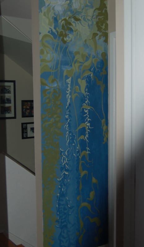 A narrow tall interior wall mural of a swaying peaceful kelp forest in greens and blues by Kathy LaFollett.