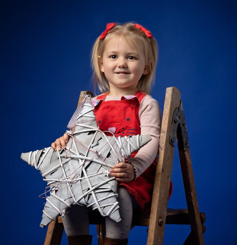 a little girl sitting on a chair with a star on it