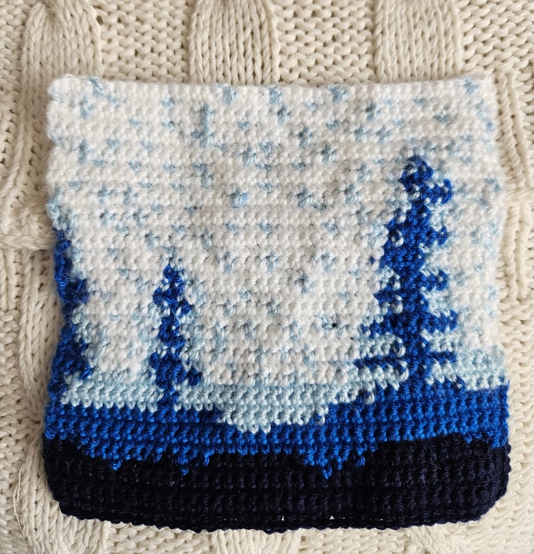 a crochet blue and white tapestry on a white pillow