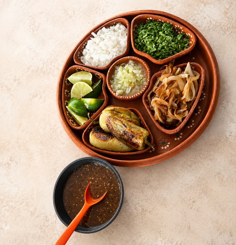 Guarniciones mexicanas frescas, salsa casera, cebolla, cilantro, limón, chiles toreados y cebolla.