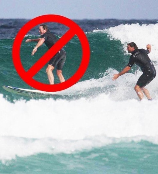 A surfer dropping in on another surfer with at red circle with a line drawn through it.