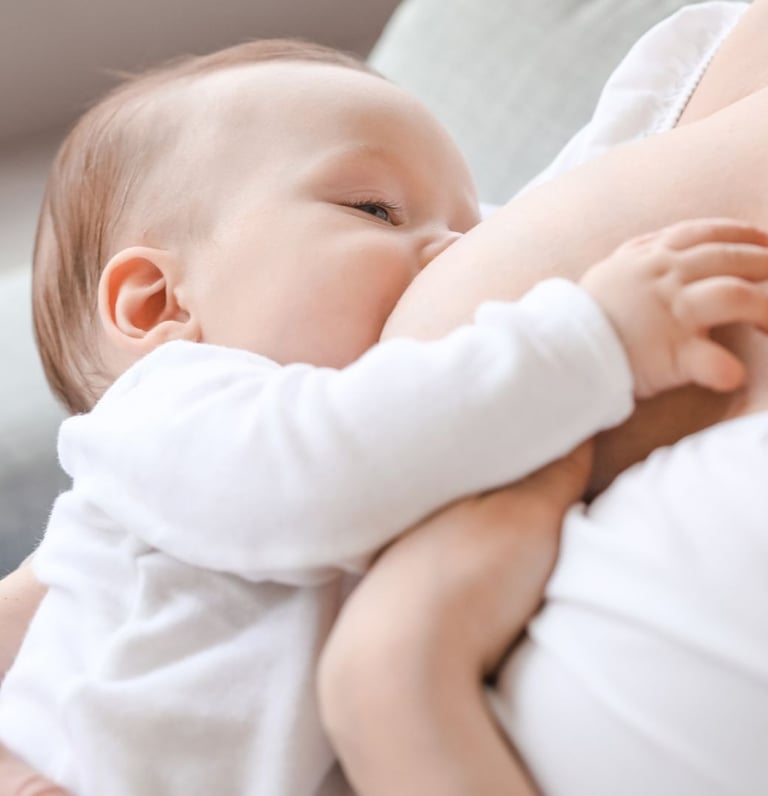IBCLC žindymo konsultantė Eglė Gurčinė padeda mamai žindyti naujagimį.