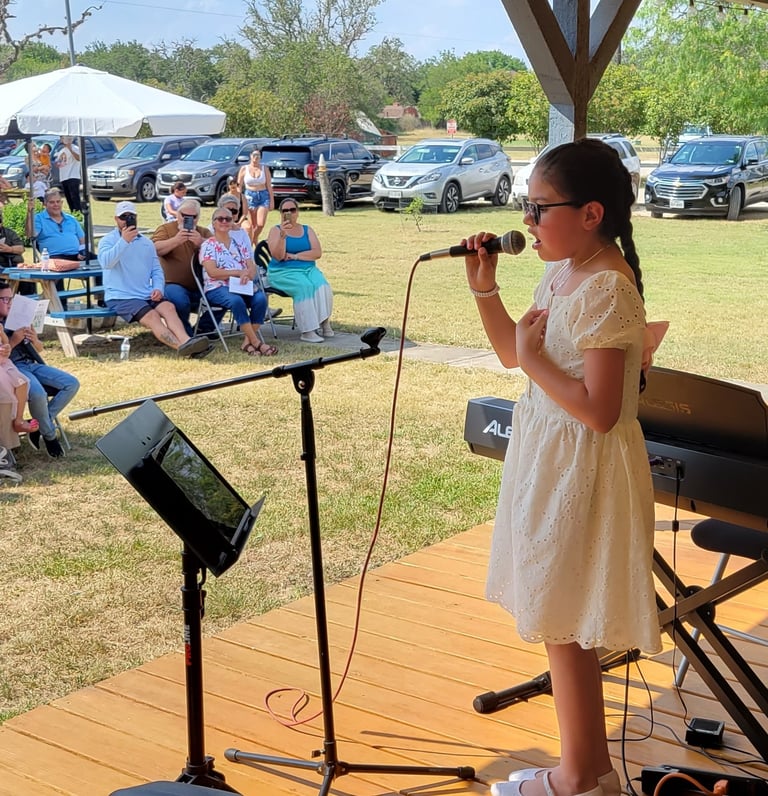 a young girl in a yellow dress is singing into a microphone 