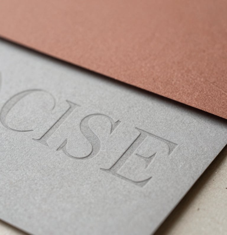Close-up of physical brand collateral with layered paper textures and debossed typography under soft natural light