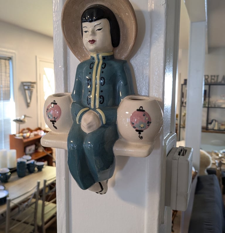 a ceramic figurine of a woman sitting on a shelf