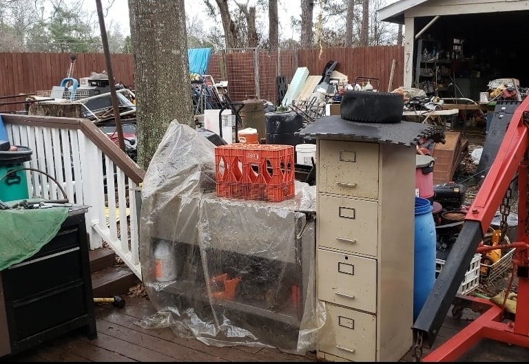 A yard filled with an overwhelming amount of junk. Old office furniture, tools, bed frames, etc.