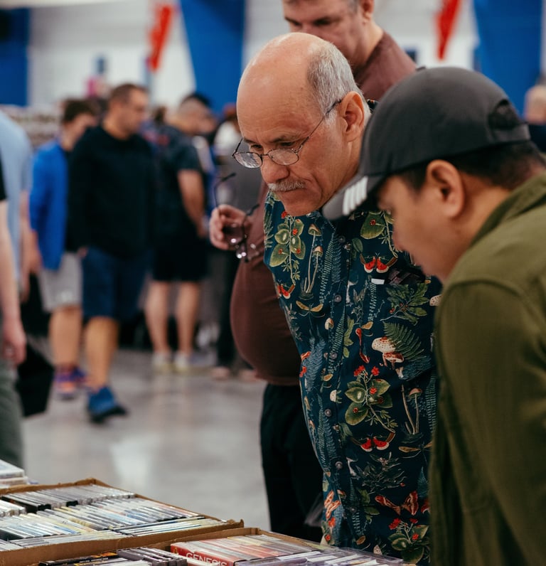 Two men look engaged and curious as they browse a selection of video games for sale.