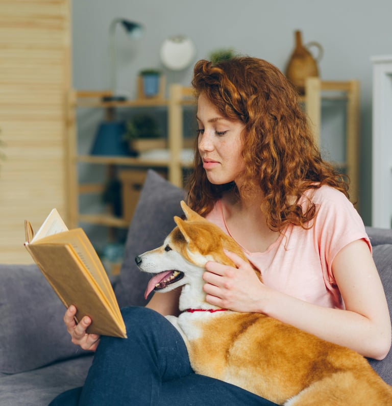 woman in her 20s reading book relaxing with dog in lap shiba inu