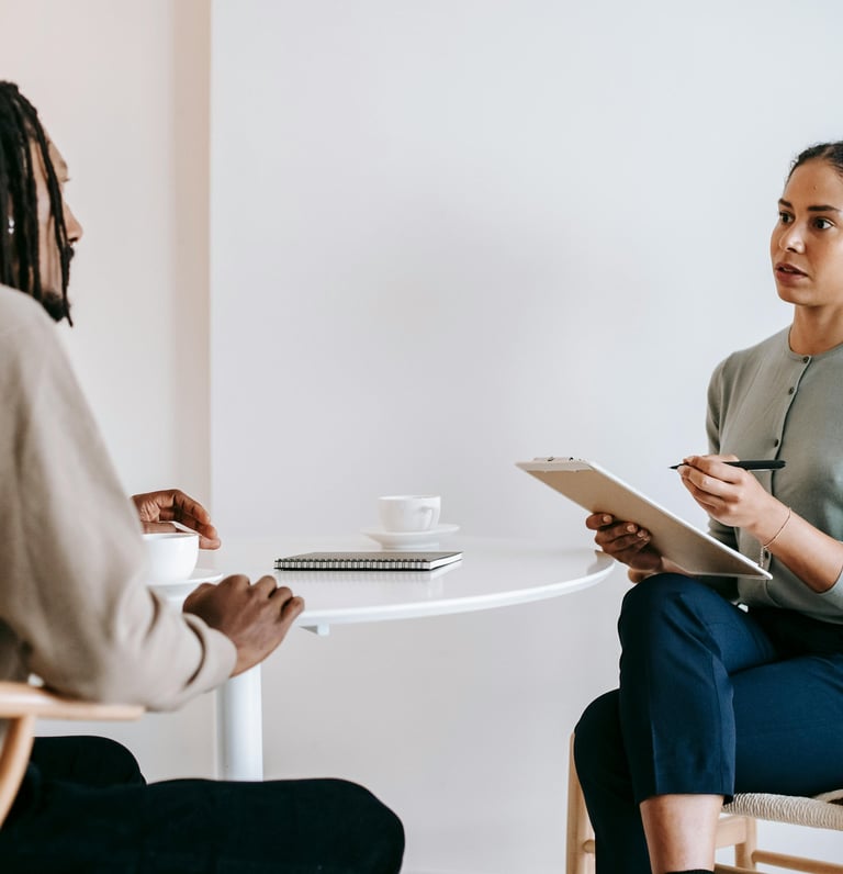 Une femme assise à une table et un homme sur une chaise en train de discuter
