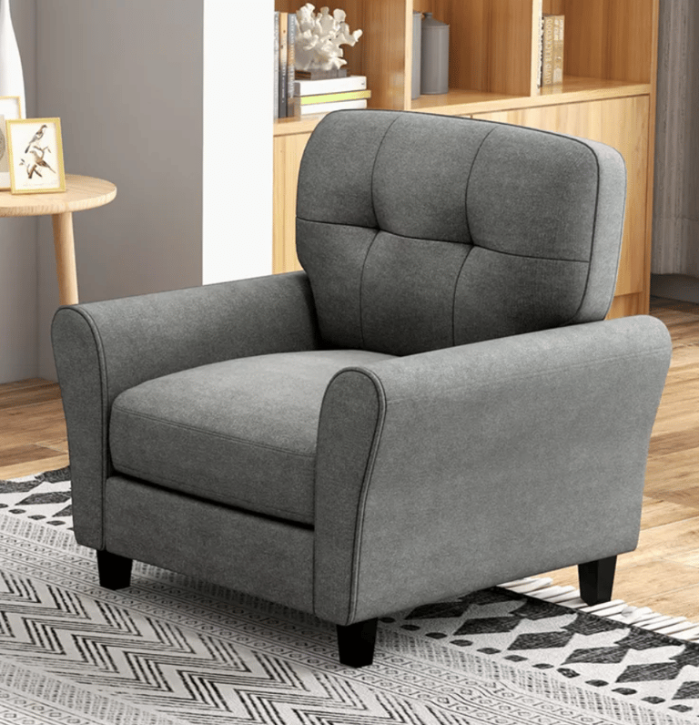 Modern grey tufted armchair with fabric upholstery in a living room setting with a patterned rug.