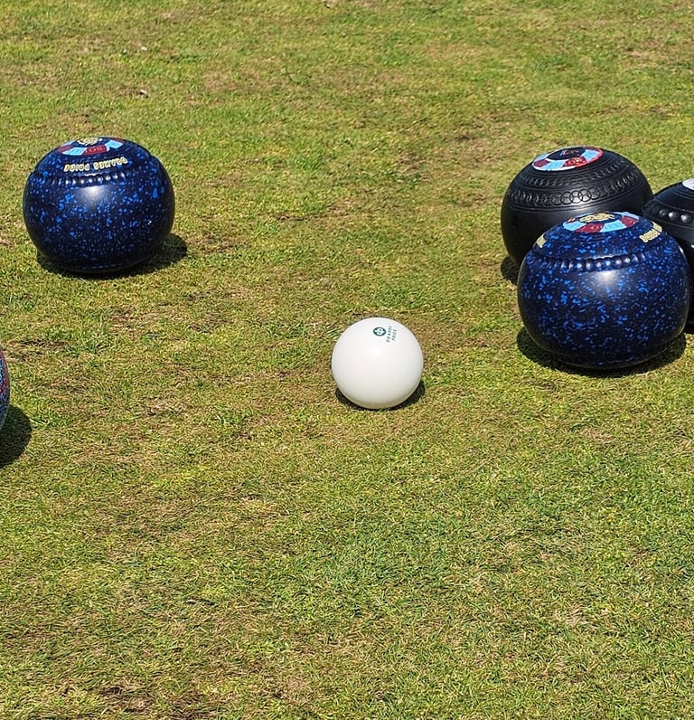 A collection of lawn bowls surrounding a white jack at porthcawl bowls club