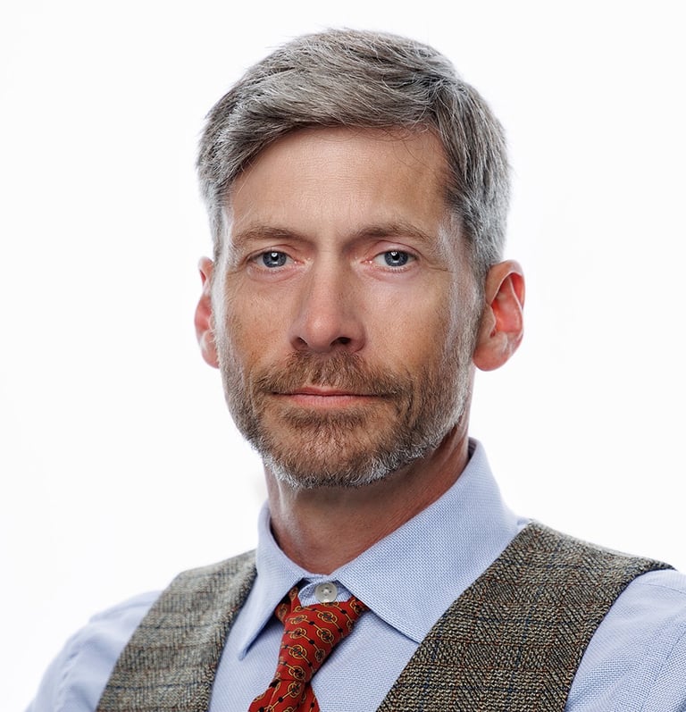 Headshot of an handsome  man with a beard on bright white backdrop.