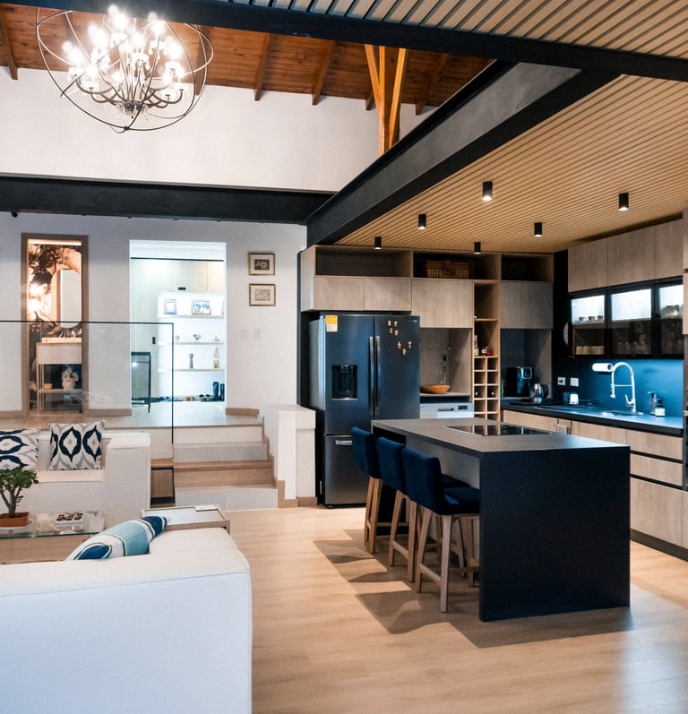 Cocina moderna de concepto abierto, isla central negra, iluminación empotrada y acabados en madera