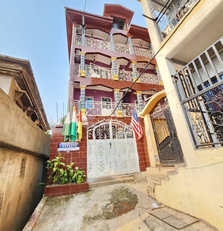 Immeuble d'appartements avec balcons en fer forgé et portail décoratif blanc. Yaoundé nsam