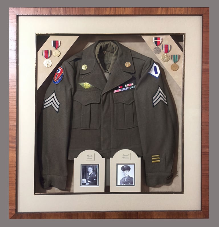 Military shadow box display featuring a vintage olive drab army uniform, medals, and portrait photos.