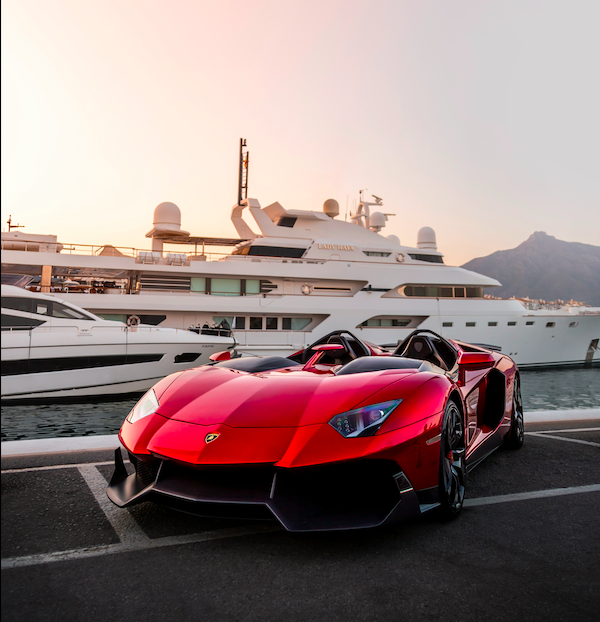 a red sports car parked in front of a yacht