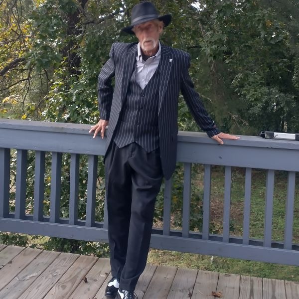 gary hagerty g in a suit and hat standing on a deck deck