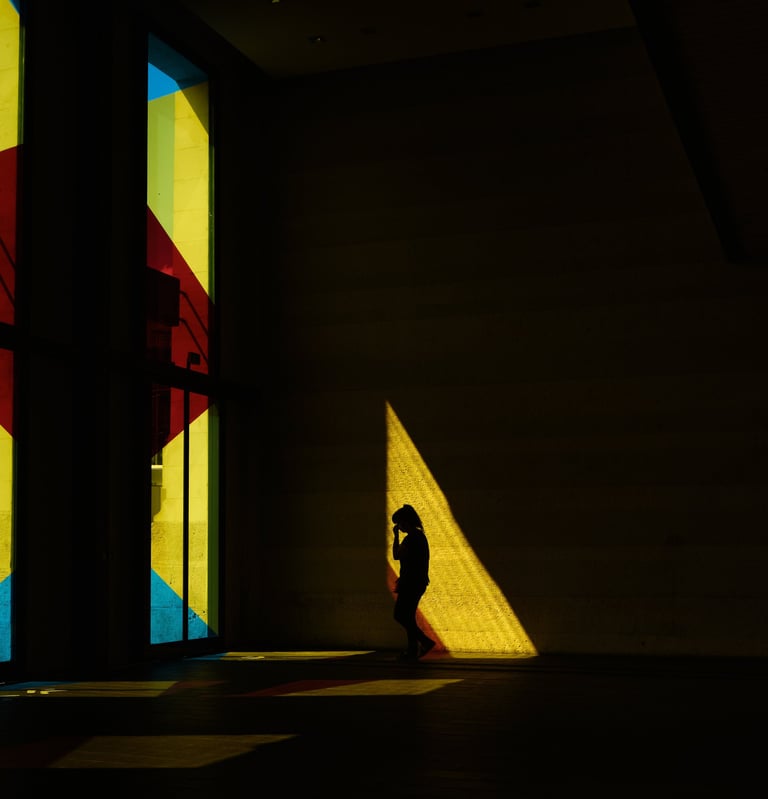 a silhouette in a train station with a colored window, and colored shapes