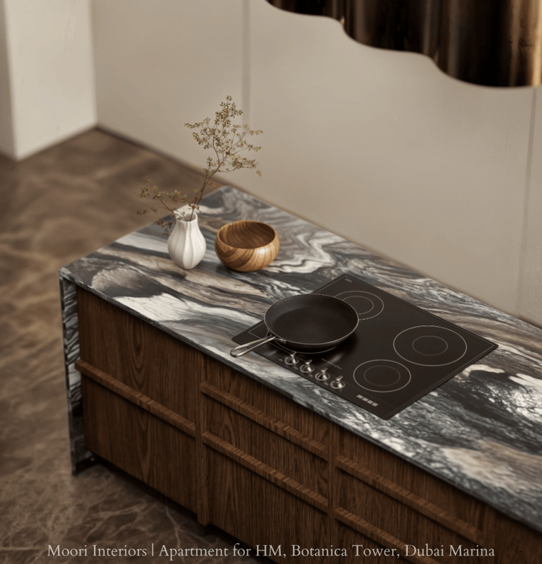 Black induction hob set into a patterned marble kitchen island with wooden cabinetry.