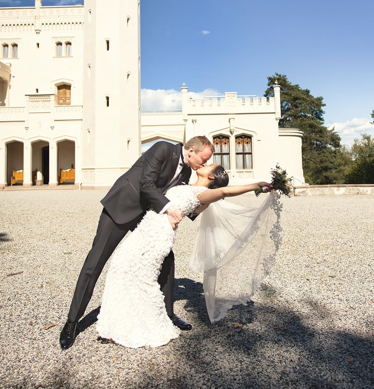 a bride and groom kissing in front of a castle