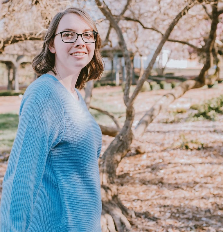Kristin Gunner, virtual assistant, in glasses and a blue sweater outside