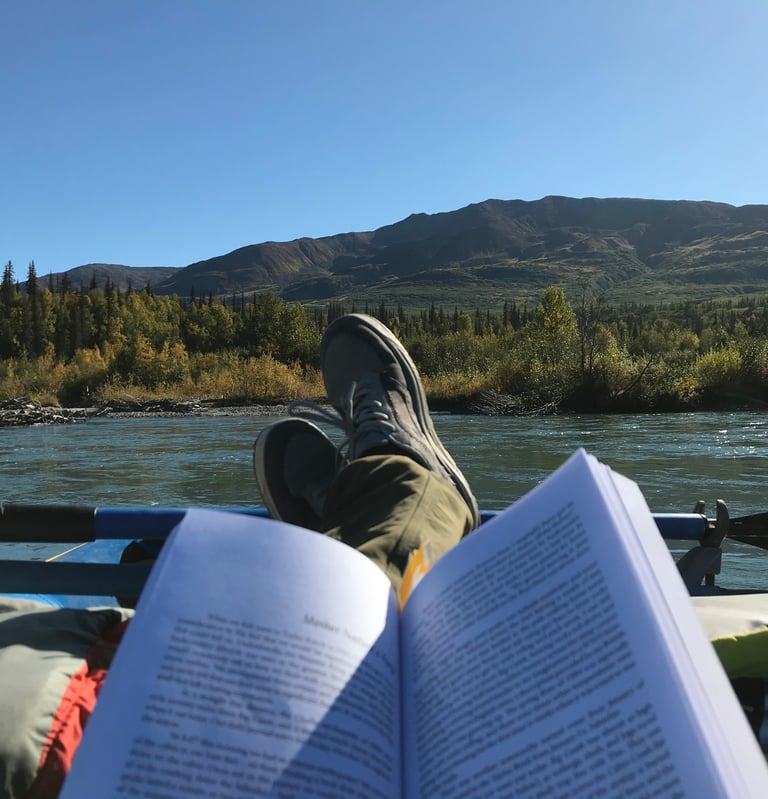 Business owner reading a book on a river
