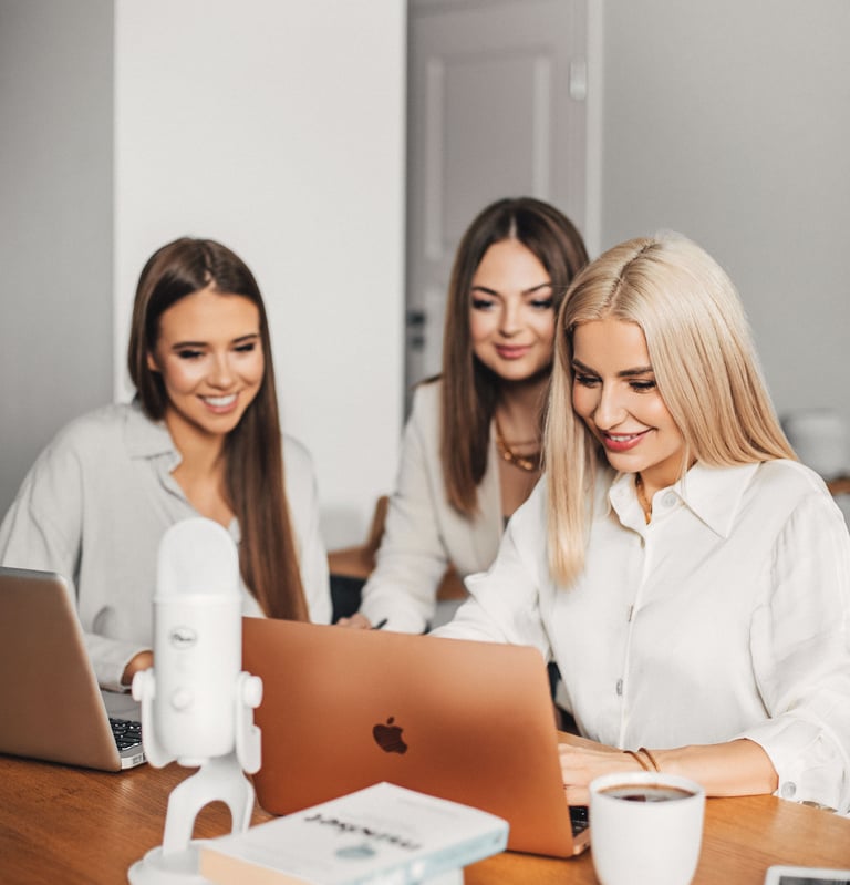 three women sitting at a table with laptops