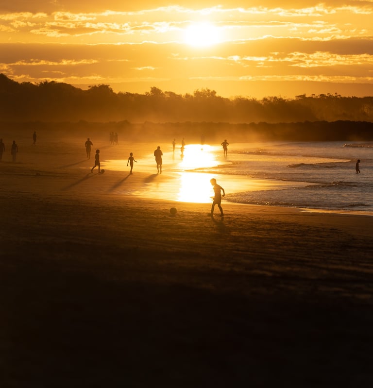 a person walking on a beach at sunset