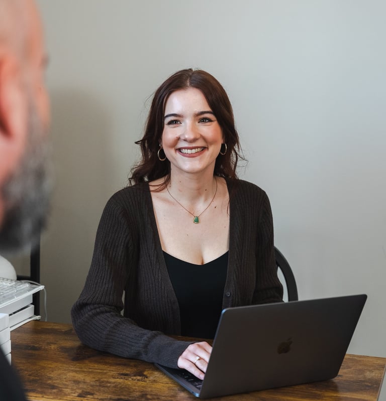 A Picture Of Abigail, the owner and founder of foundational wellness. Sitting at a desk, Smiling.