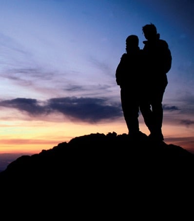 a couple of people standing on a mountain top