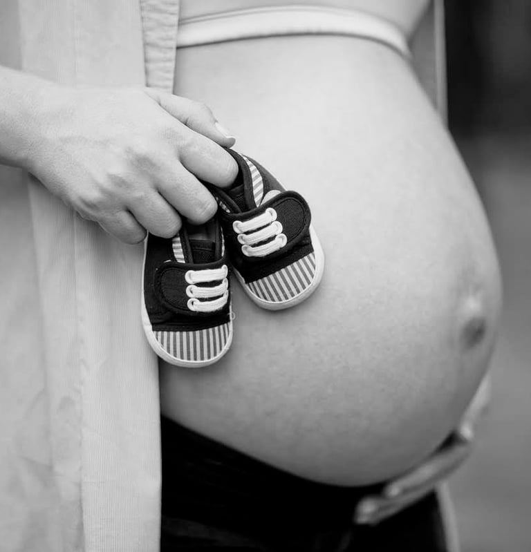 pregnant-woman-holding-baby-shoes