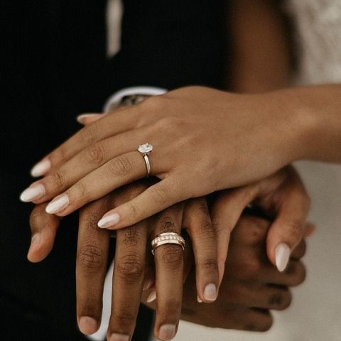 a bride and groom holding hands with their wedding rings