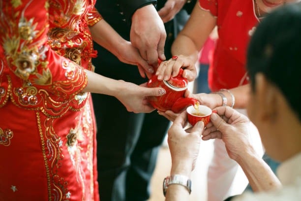a man and woman holding a red teapot