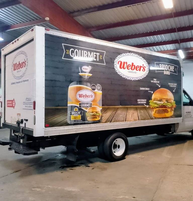A Weber's Bread delivery truck parked in a warehouse featuring gourmet brioche bun advertisements.