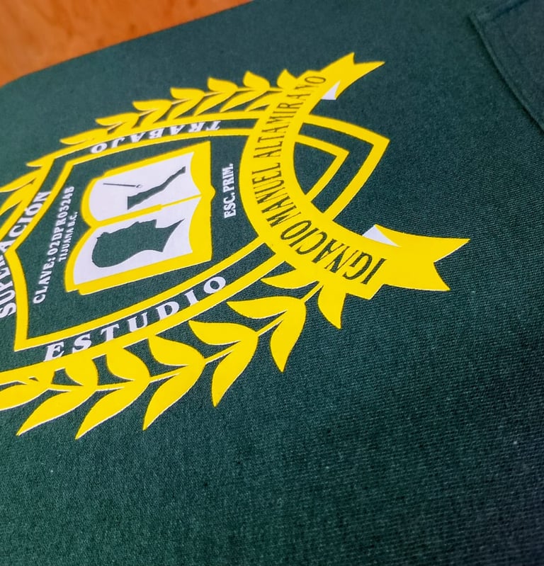 Custom screen printed yellow school crest logo on a dark green cotton t-shirt fabric.
